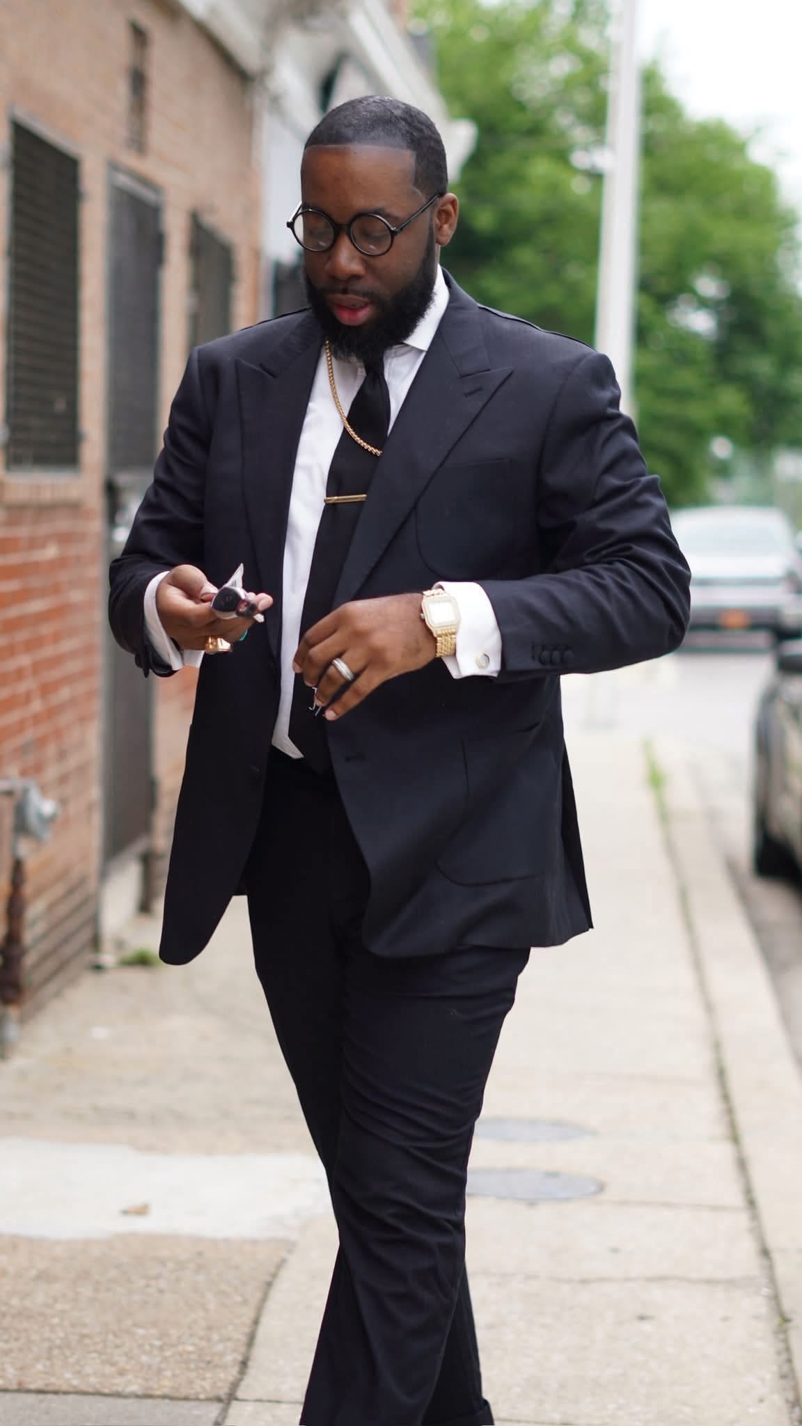 Bishop Dr. Justin Marcus in a dark suit walking outdoors